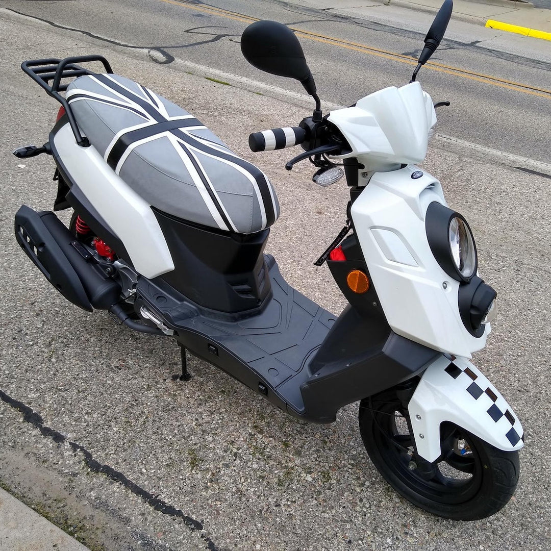 A white and black Genuine Hooligan scooter parked on an asphalt street. The scooter features a white body with black panels, a black-and-white checkered front fender accent, a Union Jack pattern on the seat, made by Cheeky Seats