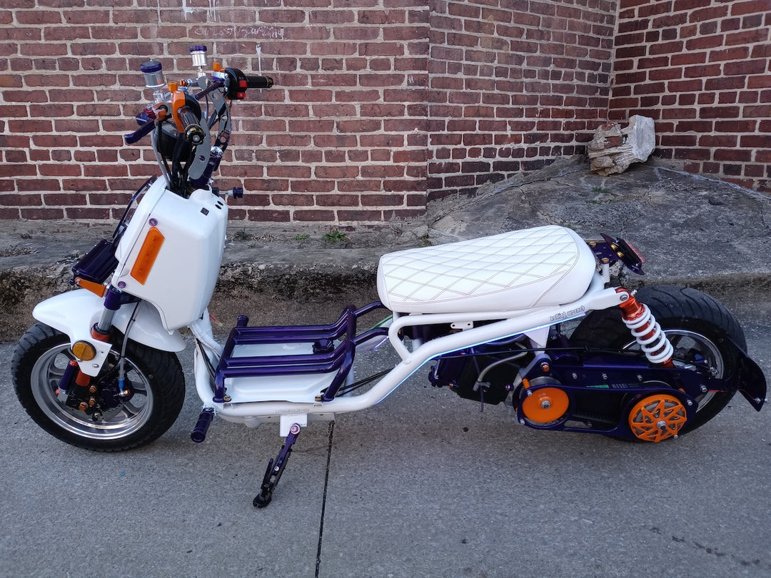 Customer photo of a white Maddog scooter with purple and orange accents featuring the white Cheeky Seats diamond seat cover