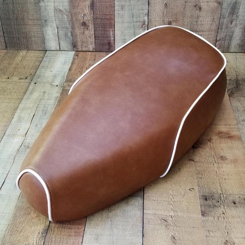 Distressed caramel brown Genuine Buddy Kick 125 seat cover with white piping, handmade by Cheeky Seats